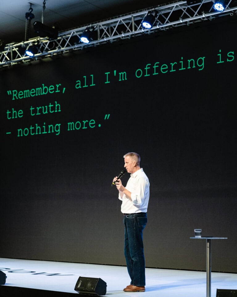 Ross standing in front of a presentation screen that says, " remember, all I am offering is the truth, nothing more."