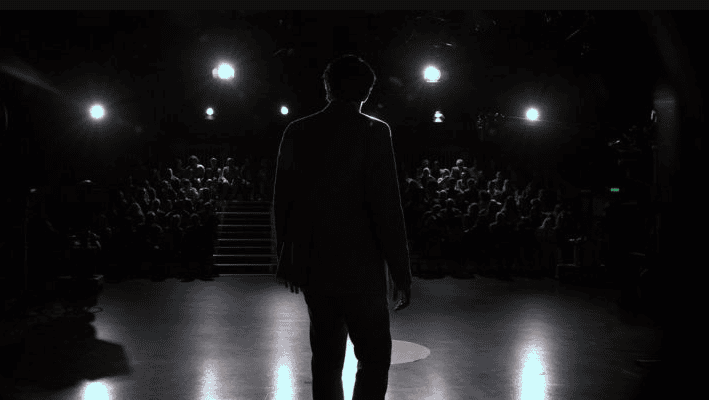 man on dark presentation stage