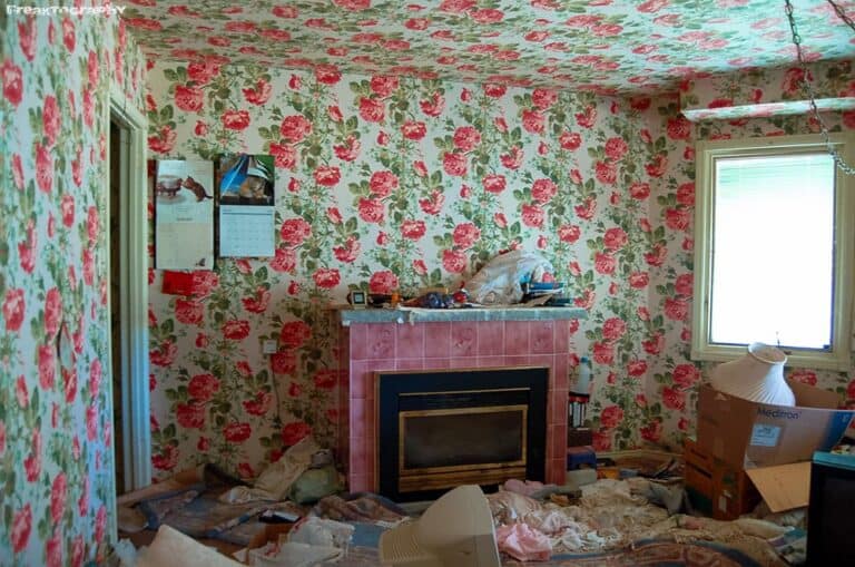 Disorganized living room with floral wallpaper and cluttered fireplace area, chaotic home interior, messy room decor, inappropriate clutter, disarrayed space.