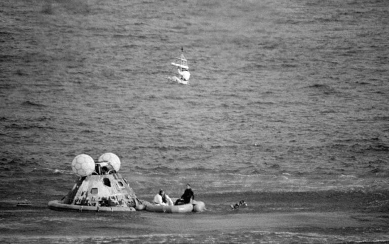 The Apollo space capsule has landed in the sea and one of the astronauts is being winched away
