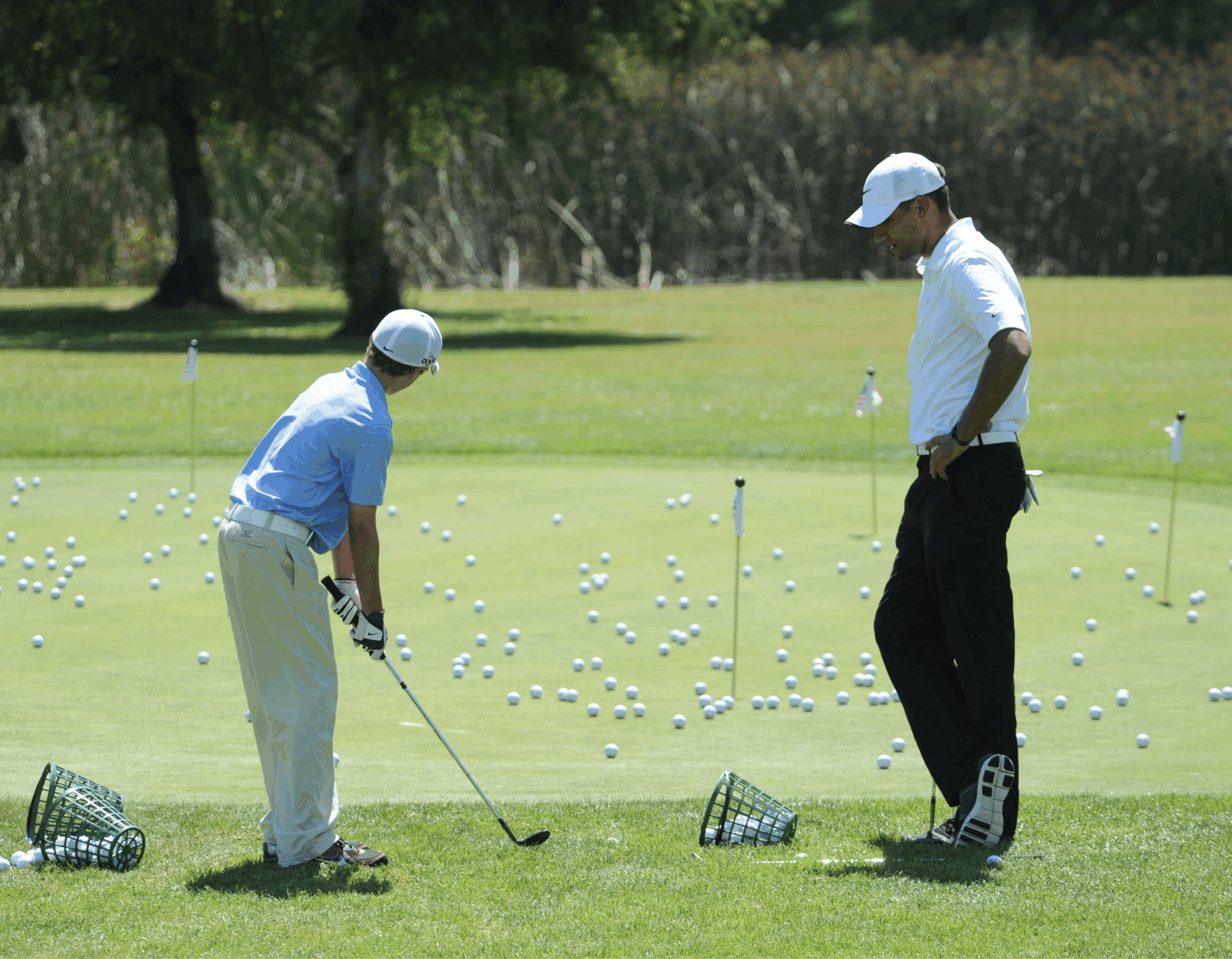 a junior golf player being coached by a senior golf player