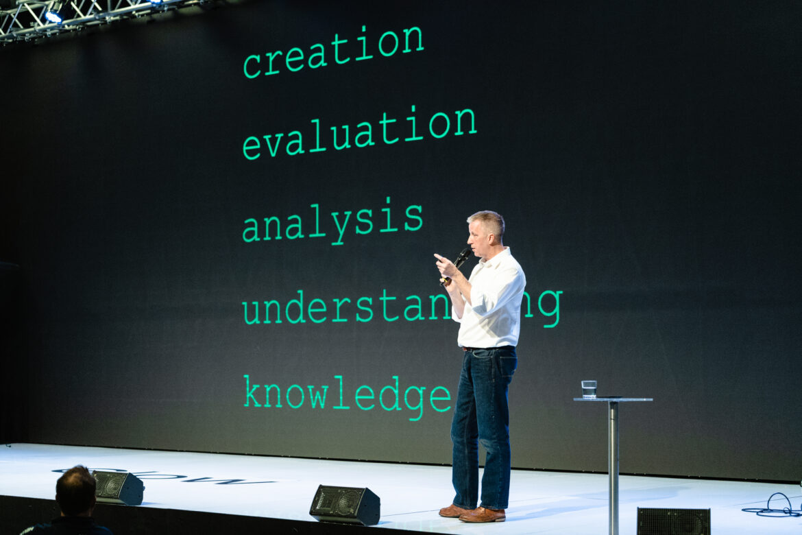 Ross standing in front of a slide of Bloom's taxonomy that describes learning