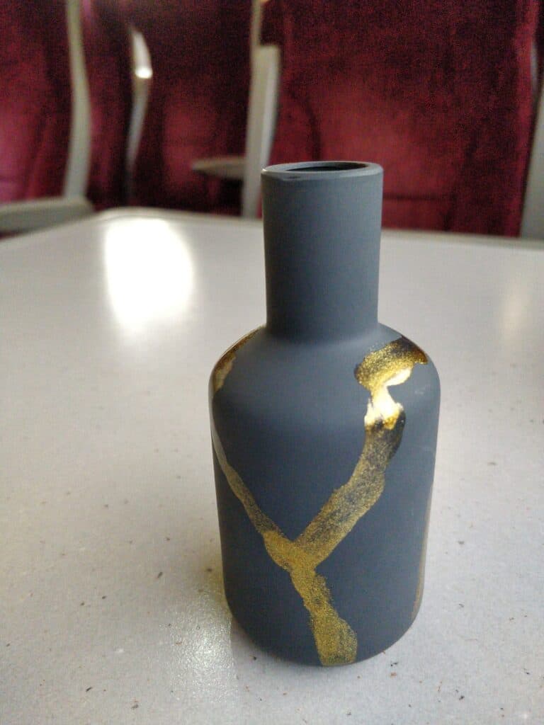 Empty artistic ceramic vase with gold accents, modern design, on a white surface, focusing on contemporary art pieces.