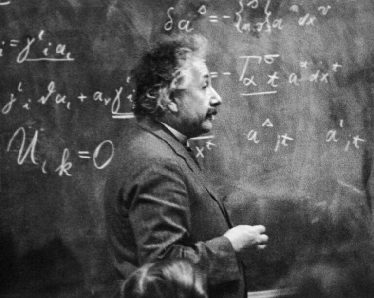 Albert Einstein stood in front of a blackboard